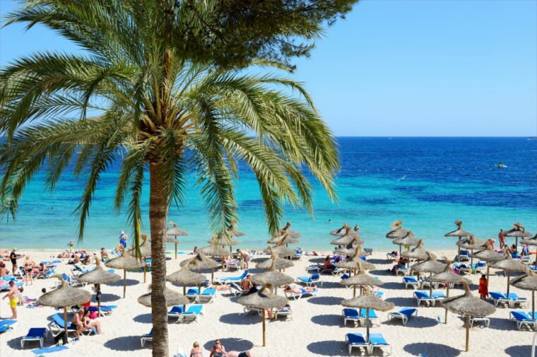 Beach umbrellas on a beach in Mallorca. See more with a Mallorca Airport car hire.